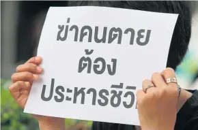  ?? PATTANAPON­G HIRUNARD ?? A capital punishment advocate holds up a sign while observing a re-enactment of a murder case in Bangkok.