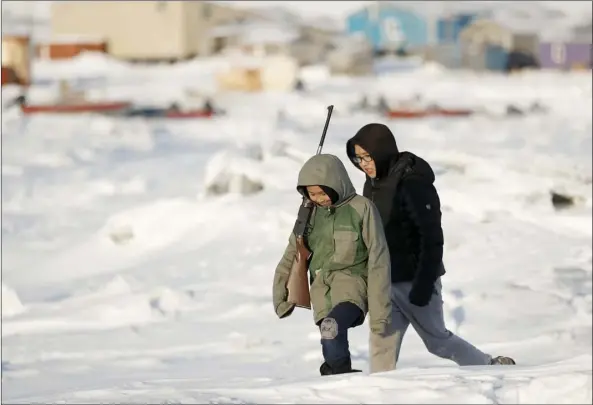  ?? AP PHOTO/GREGORY BULL ?? In this Jan. 18 file photo, George Chakuchin (left) and Mick Chakuchin walk on ice over the Bering Sea in Toksook Bay, Alaska. Motor vehicle offices across the U.S. have experience­d high demand as an Oct. 1 deadline approaches for Real IDs, special licenses many will need to board domestic flights and enter military bases and some federal buildings, but in remote parts of the country, like rural Alaska, those ID cards may be harder to get. People in Toksook Bay, on an island just off Alaska’s western coast, rely on small planes to travel off the island. The near DMV office is 115 miles away in Bethel.