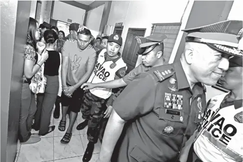  ?? MACKY LIM ?? COP BEHIND BARS. Handcuffed Police Officer 1 Glonard Maneja of the Mobile Patrol Group is being escorted by fellow cops after being presented to Davao City Police Office Director Sr. Supt. Alexander Tagum after being arrested for indiscrimi­nate firing last Sunday in his house in Matina, Davao City.