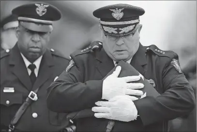  ?? [DISPATCH FILE] ?? Then-chief Joseph Morbitzer holds a flag before presenting it to officer Eric Joering’s wife, Jami, at the funeral service for Joering and officer Anthony Morelli on Feb. 16, 2018.