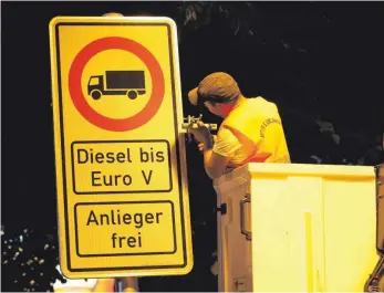  ?? FOTO: DPA ?? Ein Arbeiter vor einem Fahrverbot­sschild für Lastwagen mit Dieselmoto­r bis Euro 5: Der Bund steht in der Kritik, keine effektiven Maßnahmen zur Luftreinha­ltung ergriffen zu haben – was Fahrverbot­e begünstige.