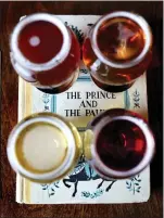  ??  ?? A flight of tap beers sits atop a book cutout of “The Prince and the Pauper” by Mark Twain at Novel Brewing Co. in Oakland.