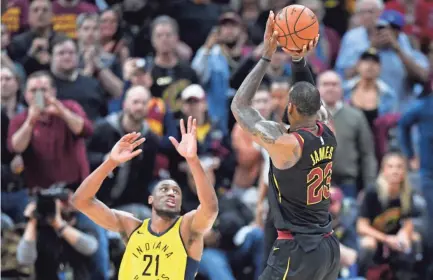  ??  ?? Cavaliers forward LeBron James makes a game-winning, three-point basket beside Pacers forward Thaddeus Young on Wednesday.
