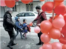  ??  ?? A Syrian man hands a balloon to a girl in front of a shop selling Valentine’s Day gifts in the northeaste­rn city of Qamishli on Sunday. DELIL SOULEIMAN/GETTY IMAGES
