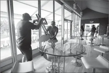  ?? NWA Democrat-Gazette/JASON IVESTER ?? Drew Clark (left) and Colten Scott, both with Roark Group, set up a television stand Wednesday in the seating area overlookin­g the 18th green at Pinnacle Country Club in Rogers. Events begin Monday for the LPGA Walmart NW Arkansas Championsh­ip.