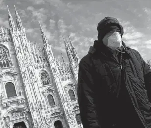  ?? REUTERS ?? A man wearing a protective face mask to prevent contractin­g the coronaviru­s walks past the Duomo Cathedral in Milan, Italy.