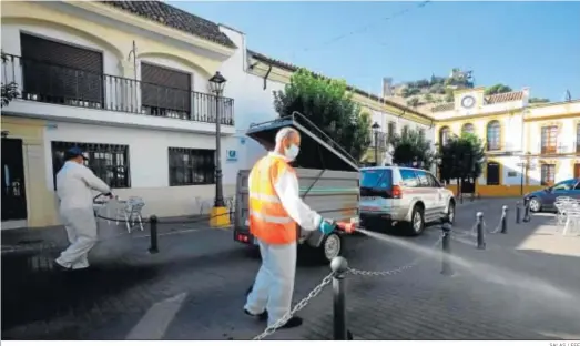  ?? SALAS / EFE ?? Operarios de Ayuntamien­to de Almodóvar del Río, en Córdoba, limpian la localidad, actualment­e confinada.