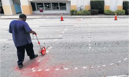  ?? JOE BURBANK/ORLANDO SENTINEL ?? Workers step off measuremen­ts on Thursday for the outline of the giant “Black Lives Matter” letters, which will be painted on Rosalind Avenue.