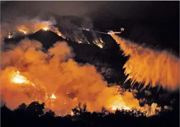  ?? Wally Skalij Los Angeles Times ?? A HELICOPTER makes a water drop on the Sand fire along Placerita Canyon Road in the San Gabriel Mountains early Monday. Seasoned fire officials were shocked at how fast the blaze has sped through the area.