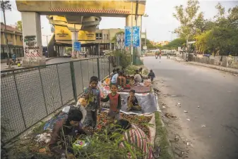  ?? Yawar Nazir / Getty Images ?? Homeless people sit on the side of a deserted road in New Delhi after the prime minister decreed a “total lockdown” of the country of 1.3 billion people for 21 days.