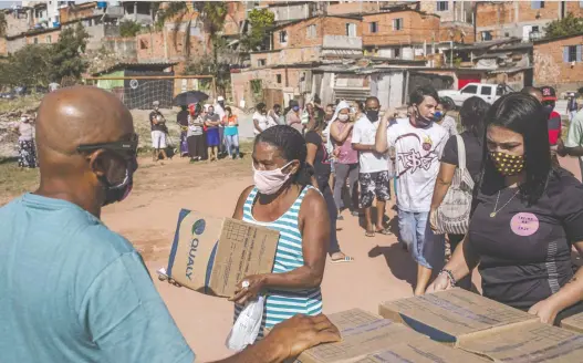 ?? VICTOR MORIYAMA/ BLOOMBERG ?? Volunteers distribute boxes of food and hygiene products to residents of a favela in Sao Paulo, Brazil.
