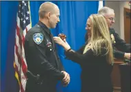  ??  ?? Marie pins a badge on her husband and newly promoted Lt. Eric Versteeg at Carnegie Forum in Lodi on Thursday.