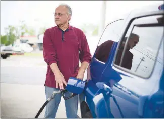  ??  ?? Tom Sech, who likes to make trips to his lakeside cottage in Chautauqua, N.Y., fills up his Chevy on Friday at a Shell gas station in Valley View, Ohio. “I can go more often because gas is cheaper,” Sech said, of his trips.