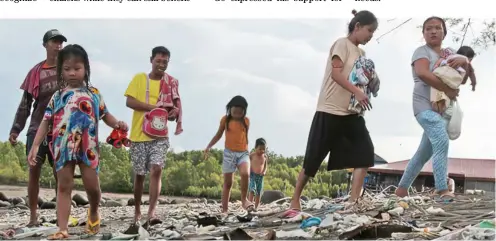  ?? PHOTOGRAPH BY JOEY SANCHEZ MENDOZA FOR THE DAILY TRIBUNE ?? A FAMILY looks into piles of garbage brought by the low tide along the shorelines of a public beach resort in Punta Taytay, Bacolod City on Friday morning.