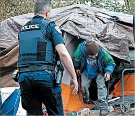  ?? ELAINE THOMPSON/ASSOCIATED PRESS ?? Everett, Wash., police officer Kevin Davis, left, and Sgt. Mike Braley check on a resident living in a tent in the woods.