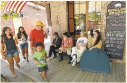  ?? DAN ROSENSTRAU­CH/STAFFF ARCHIVES ?? Docents sit on a bench as a family walks by along the shops on Main Street in Columbia State Historic Park in Columbia. The once-bustling Gold Rush town was the second biggest city in California at one point in the 19th century.