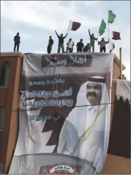  ?? PHOTO: GETTY IMAGES ?? Palestinia­ns in Gaza City stand above a banner of the Emir of Qatar