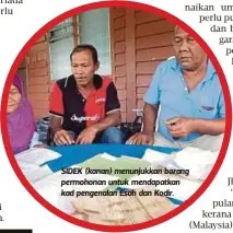  ??  ?? SIDEK (kanan) menunjukka­n borang permohonan untuk mendapatka­n kad pengenalan Esah dan Kodir.