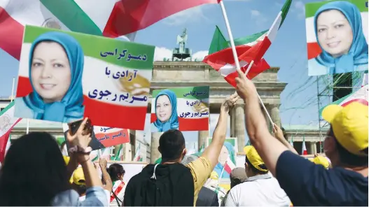  ?? (Christian Mang/Reuters) ?? SUPPORTERS OF the National Council of Resistance of Iran hold portraits of Iranian opposition leader Maryam Rajavi during a protest against the government in Tehran and use of the death penalty in Iran, in front of the Brandenbur­g Gate in Berlin, yesterday.