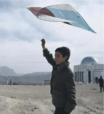  ?? AFP ?? An Afghan boy prepares his kite for flight during a ‘battle’ between flyers on a hillside in Kabul. The traditiona­l pastime has endured despite war and repression by the Taliban