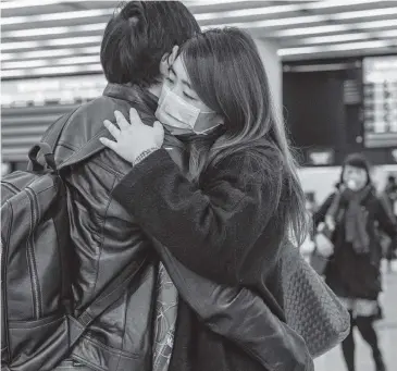  ?? ANTHONY KWAN Getty Images ?? A couple wearing protective masks make their farewell at a Hong Kong rail station on Wednesday.