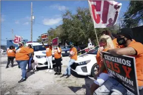  ?? JOHN RAOUX ?? Cristian Cardona, sitting on a car hood, center, an employee at a Mcdonald’s, attends a rally for a $15 an hour minimum wage Tuesday, Feb. 16, 2021, in Orlando, Fla.