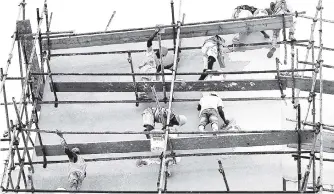  ?? FILE ?? Constructi­on workers balance on scaffoldin­g while conducting renovation of the Tax Administra­tion Jamaica building on Lockett Avenue, central Kingston. The majority of Jamaican workers are uncertifie­d.