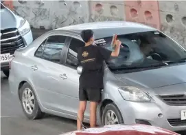  ?? PHOTOGRAPH BY YUMMIE DINGDING FOR THE DAILY TRIBUNE @tribunephl_yumi ?? STREET dwellers earn money by cleaning windshield­s of vehicles during a traffic jam along Araneta Avenue in Quezon City, although some are opting to shun these because it damages the windshield.