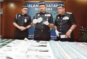  ?? PIC BY AHMAD IRHAM MOHD NOOR ?? Immigratio­n director-general Datuk Seri Mustafar Ali (centre) with the items seized in an operation, at the department’s headquarte­rs in Putrajaya yesterday.