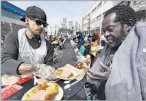  ??  ?? WITH MIDNIGHT Mission, volunteers such as Brian Burnham, left, hand out meals to men, women and children in skid row.