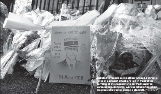  ?? Photo: AFP ?? Tributes to French police officer Arnaud Beltrame killed in a jihadist attack are laid in front of the barracks of the gendarmeri­e on Wednesday in Carcassonn­e. Beltrame, 44, was killed after taking the place of a woman during a standoff.