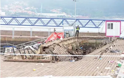  ?? — Gambar Carmelo Alen/AFP ?? PEGAWAI penyiasat polis memeriksa pelantar di tepi laut di Vigo kelmarin selepas satu bahagian sesiaran kayu tiba-tiba runtuh ketika orang ramai menyaksika­n persembaha­n artis rap sebelum tengah malam Ahad lalu.