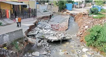  ?? — DEEPAK DESHPANDE ?? Locals look at a portion of the road that had caved in during the rain at Shanti Vihar Colony in Kapra on Monday. GHMC officials cleared encroachme­nts on the road that was blocking the flow of water.