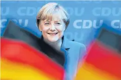  ?? AP ?? Chancellor Angela Merkel smiles behind German flags at the party headquarte­rs in Berlin, after her party scored a landslide victory in elections held on Sunday.