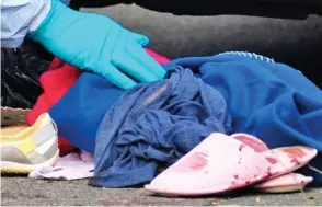  ?? ?? Aftermath: Forensics officers examine bloody clothes at the scene