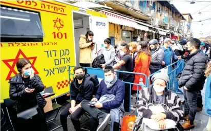  ?? (Olivier Fitoussi/Flash90) ?? PEOPLE WAIT to receive their COVID-19 vaccine injections outside a mobile Magen David Station at the Mahaneh Yehuda market in Jerusalem, on Monday.