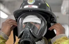  ??  ?? Michael Franklin, a junior at Westinghou­se Academy, makes adjustment­s to his firefighti­ng equipment.