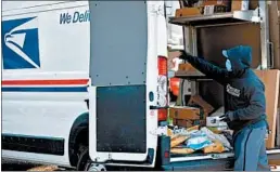  ?? SAUL LOEB/GETTY-AFP ?? A postal worker wearing a mask and gloves loads a truck with packages at a post office in Washington.