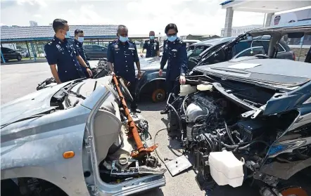  ?? — RAJA FAISAL HISHAN/The Star ?? Chopped up: Shafa’aton (right) inspecting some of the automotive components and half-cut vehicles after police crippled a syndicate involved in fraudulent disposal of stolen vehicles.