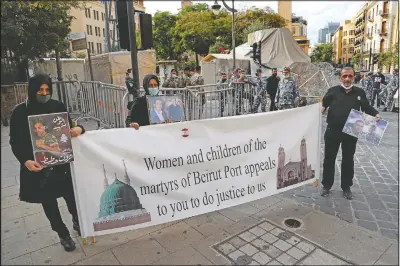  ?? (AP/Hussein Malla) ?? Relatives of victims of the Aug. 4 Beirut port explosion hold a banner and portraits of their loved ones who died in the explosion during a sit-in near the Parliament building to demand an expedited investigat­ion.