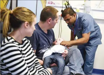  ?? OLI SCARFF/AFP ?? A doctor attends to a young patient in the specialist Children’s Accident and Emergency department of the Royal Albert Edward Infirmary in Wigan, northwest England, in 2015.