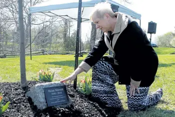  ?? LAURA BARTON/POSTMEDIA NETWORK ?? Tracey Merrett pauses a moment with the plaque placed at the base of a tree planted in memory of her husband Brian Merrett at the Peace Garden in Cooks Mills on Sunday.