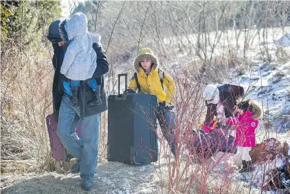  ?? GRAHAM HUGHES/ THE CANADIAN PRESS ?? A man and his family cross the U.S.-Canada border in Hemmingfor­d, Que., last week. Martin Collacott says failing to find solutions to people entering the country illegally could result in public backlash.