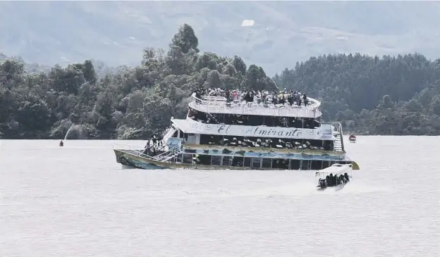  ?? PICTURE: JUAN QUIROZ/AP ?? 0 A small boat rushes to the assistance of the El Almirante as she begins to sink, a disaster that left six dead and many missing