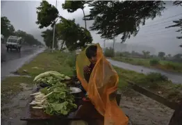  ?? — AP ?? A boy selling vegetables by a roadside covers himself with a plastic sheet during heavy monsoon rain in Greater Noida on Saturday.