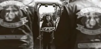  ??  ?? Sue Ellen Davis holds a flag at the grave of her father. Davis had tried to move him into her Angleton home, but the coronaviru­s spread to his assisted-living facility before she could.