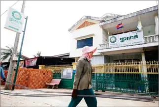  ?? POST PIX ?? A constructi­on worker walks past a Prasac Microfinan­ce Institutio­n branch in Kampot province’s Kampong Bay Khang Choeung village.