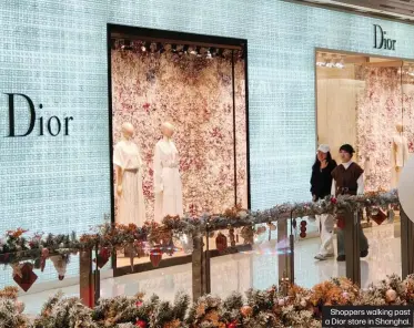  ?? ?? Shoppers walking past a Dior store in Shanghai.