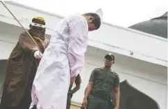  ?? CHAIDEER MAHYUDDIN / AFP / GETTY IMAGES / FILES ?? An Acehnese man convicted for “immoral acts” is lashed by a hooded local government officer during a public caning in 2015 in Banda Aceh.