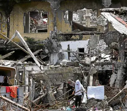  ?? —JEOFFREY MAITEM ?? REHABWORK Muslim women survey the damage after government forces drove terrorists out of Marawi City. A community-led rehabilita­tion is relevant, as “many precolonia­l, traditiona­l and informal governance structures and practices around land, housing...